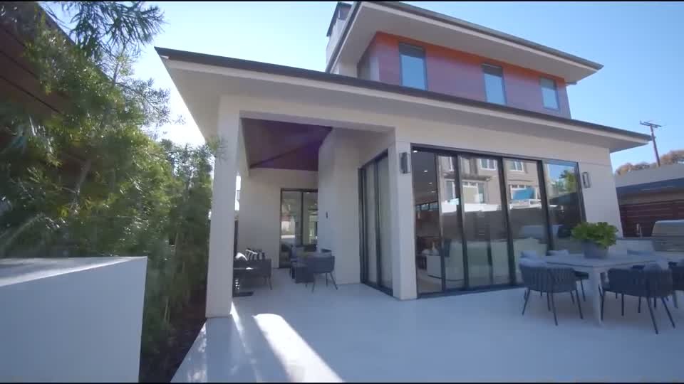 Rear exterior of the Hampton house in the source tour video: a two-storey home with a covered alfresco terrace and outdoor dining.